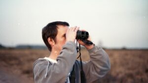Hombre mirando con prismáticos al horizonte para crear una visión estratégica